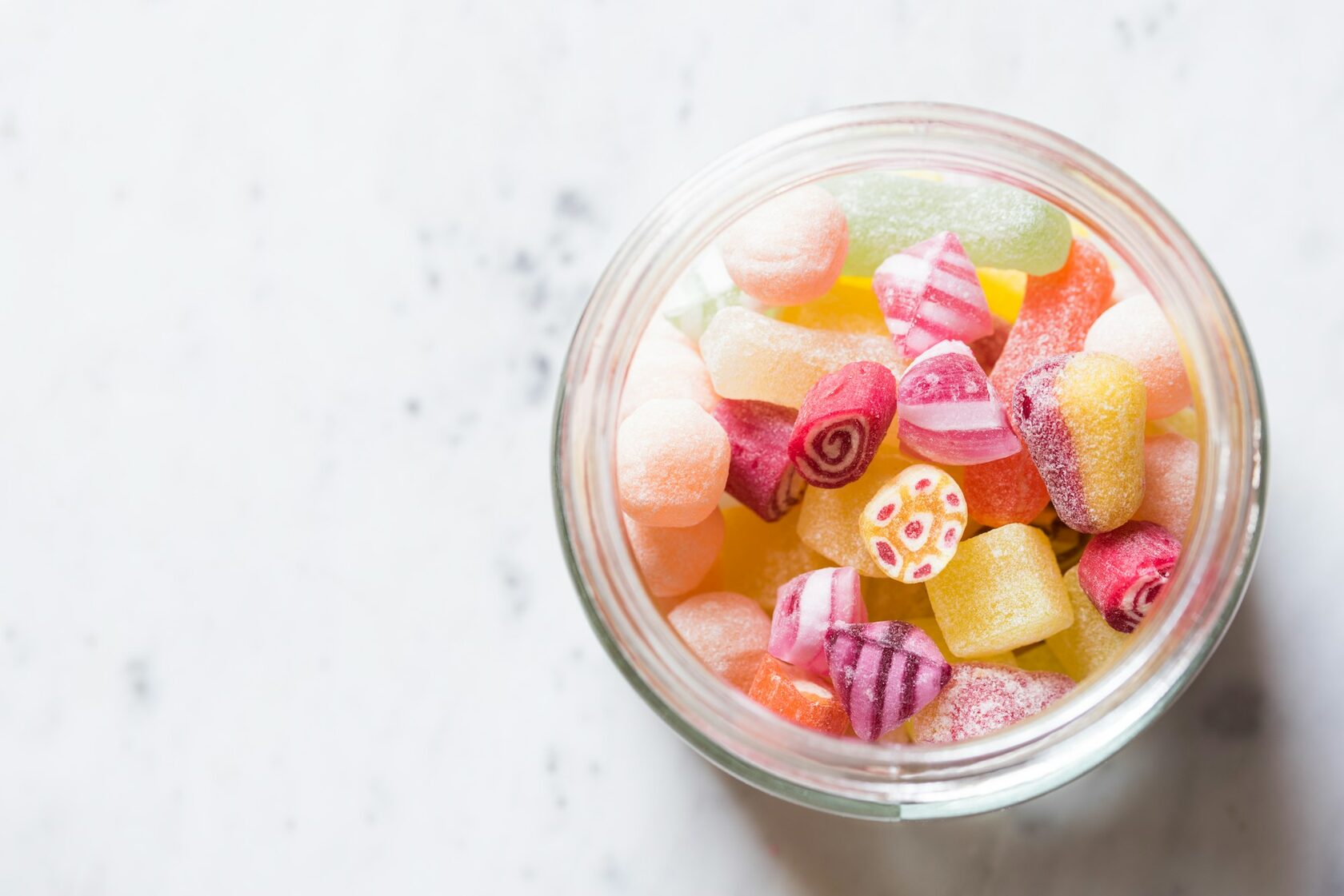 A colourful jar of round Coin Volcano candies in many fruity flavours